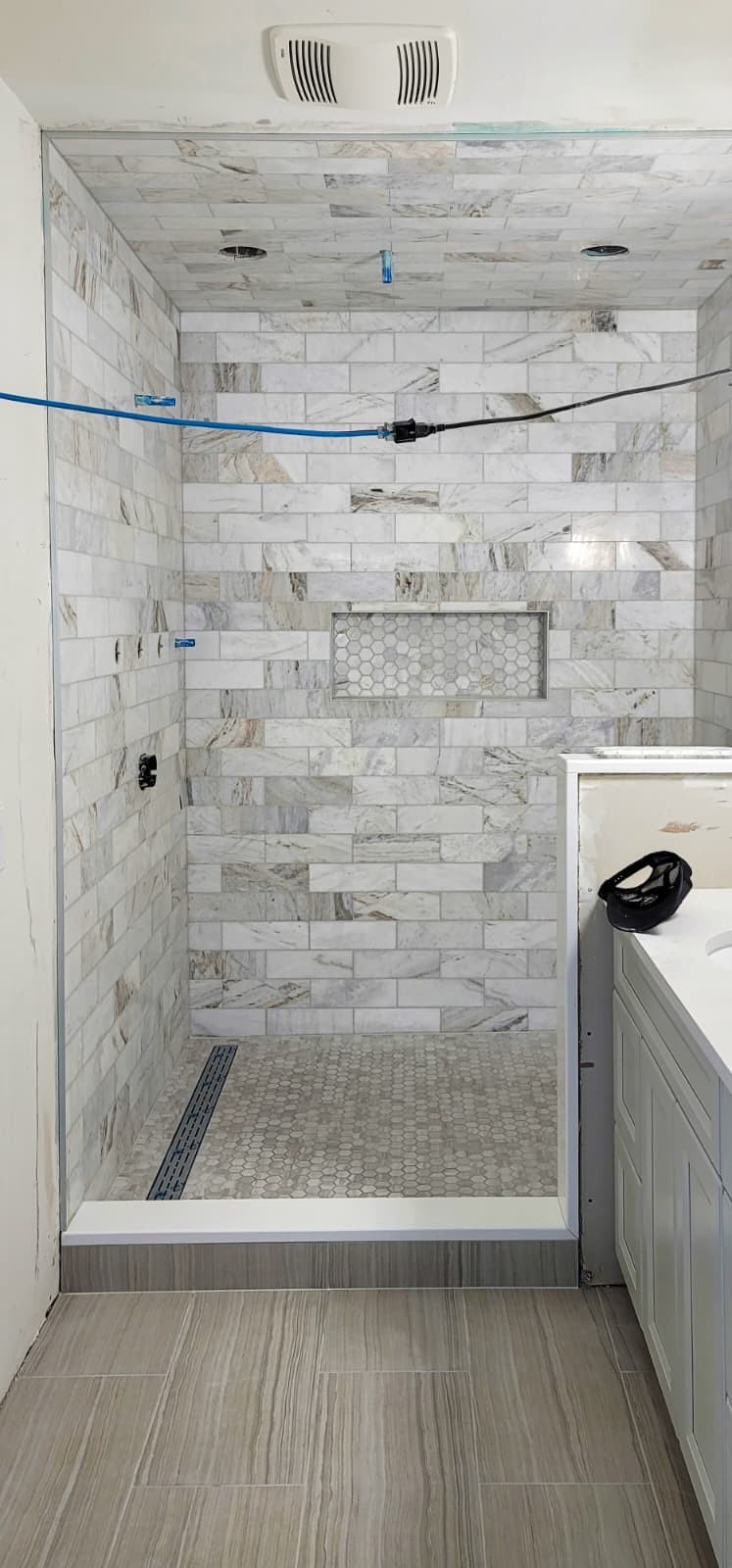 Low-profile walk-in shower with linear drain and mosaic floor