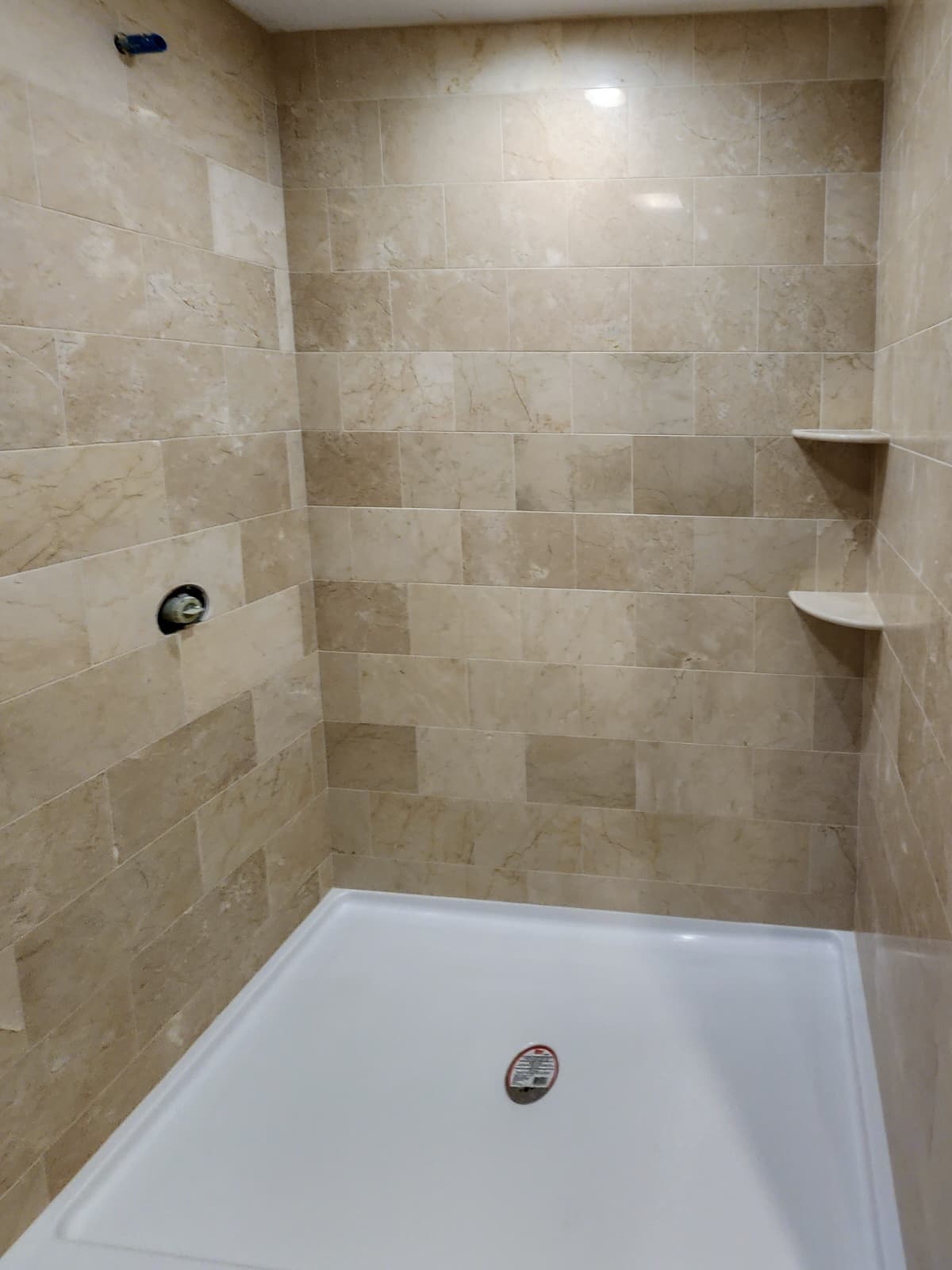 Beige natural stone-look shower wall tile with corner shelves