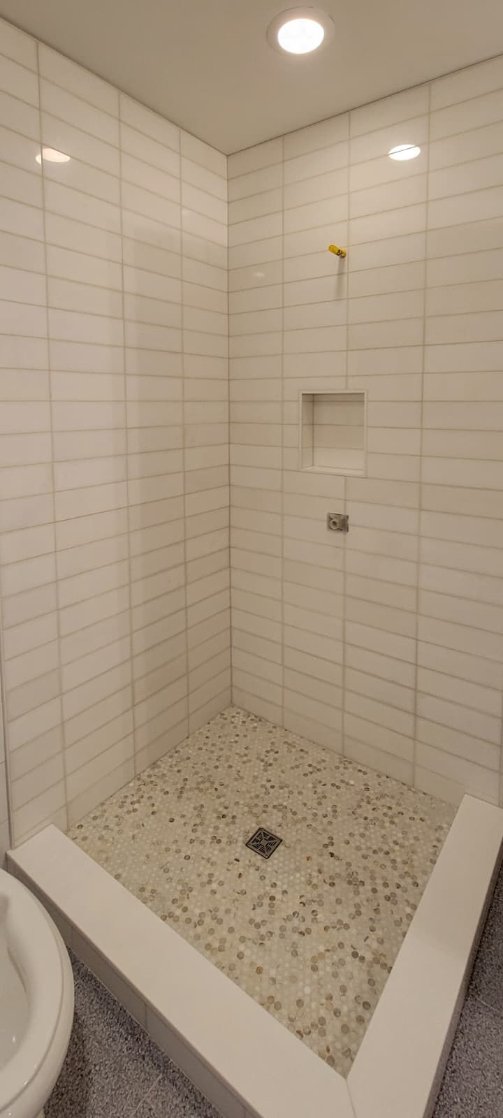 Built-in shower bench with dark green subway tile face