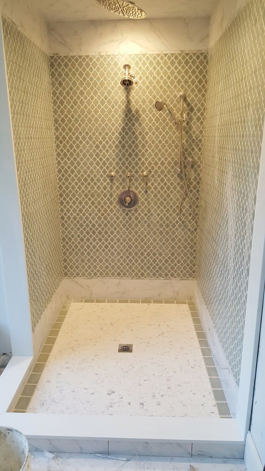 Tall walk-in shower with arabesque mosaic wall tile, handheld shower and white tile floor
